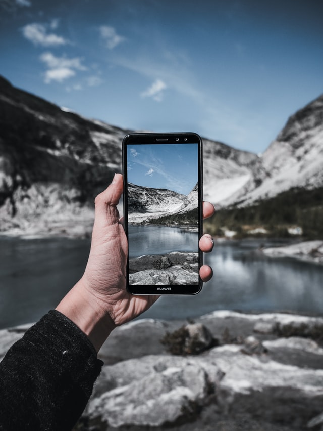 A generic smartphone being used to take a picture of a mountain scene